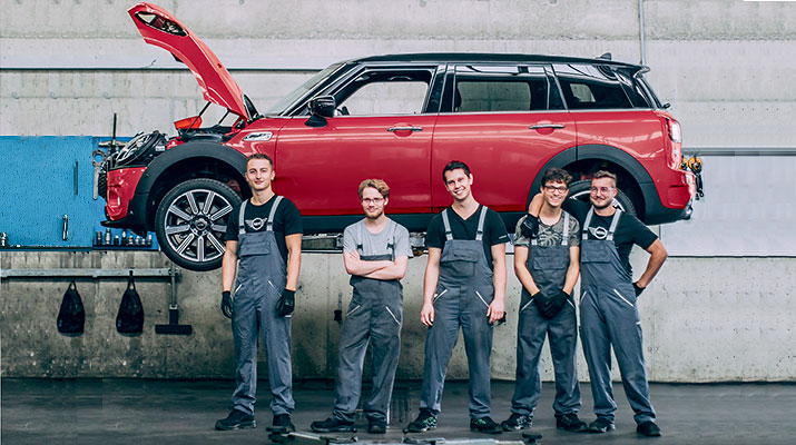 Vediamo un team di meccanici all'interno di un'officina davanti ad una MINI rossa con il cofano aperto.